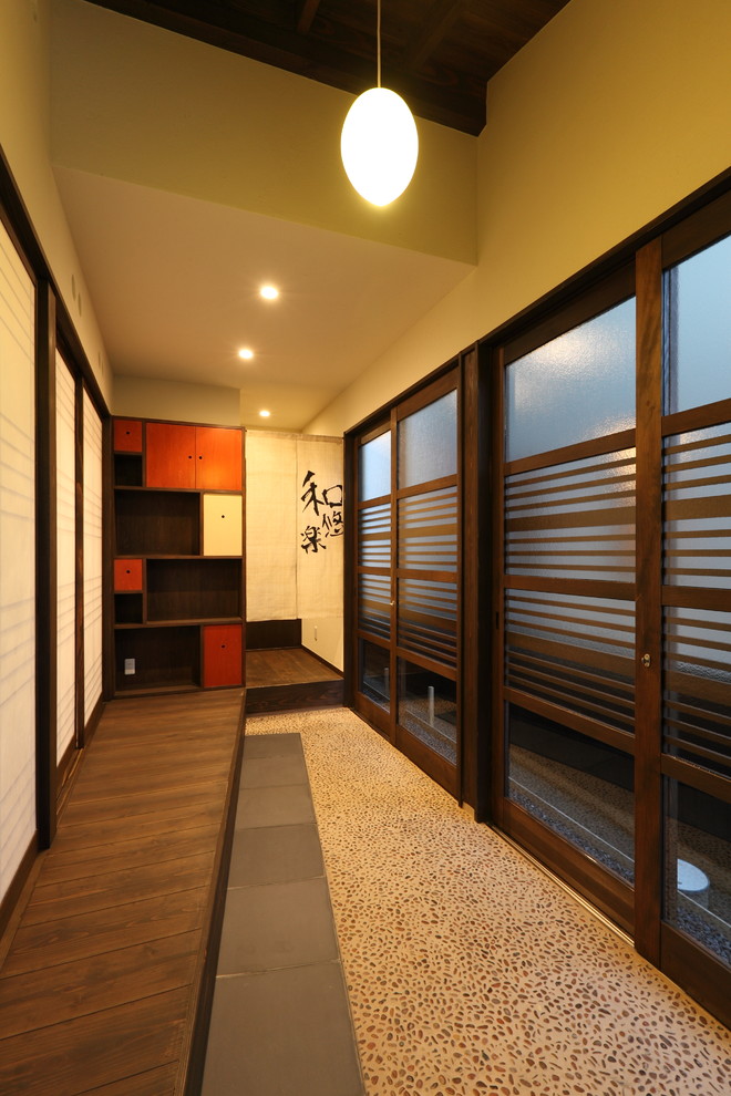 This is an example of a mid-sized asian front door in Other with brown walls, a sliding front door, a dark wood front door and grey floor.