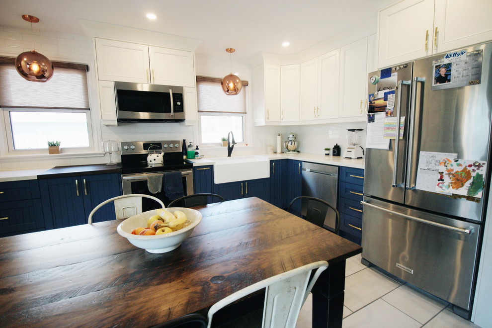 Mid-sized transitional u-shaped porcelain tile and multicolored floor eat-in kitchen photo in Toronto with a farmhouse sink, beaded inset cabinets, blue cabinets, quartzite countertops, white backsplash, ceramic backsplash, stainless steel appliances, no island and multicolored countertops