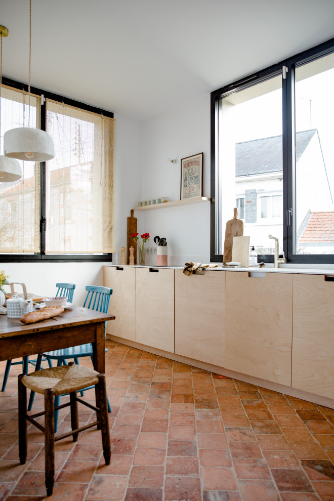 ナントにある高級な中くらいなトラディショナルスタイルのおしゃれなキッチン (淡色木目調キャビネット、白いキッチンパネル、テラコッタタイルの床、白いキッチンカウンター) の写真