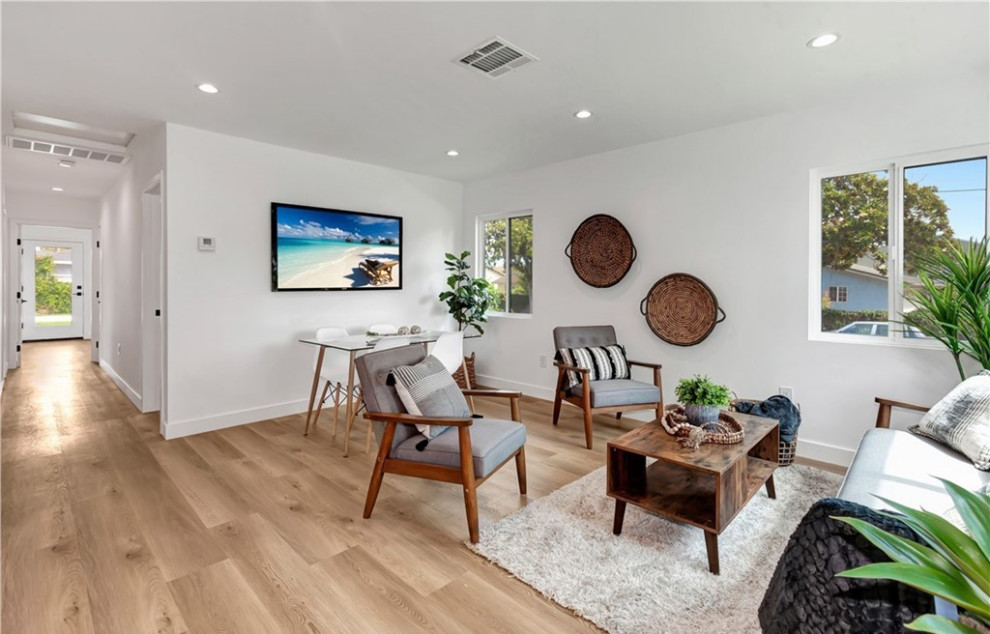 Cette image montre un salon design ouvert avec un mur blanc, un sol en bois brun, un téléviseur fixé au mur et un sol marron.