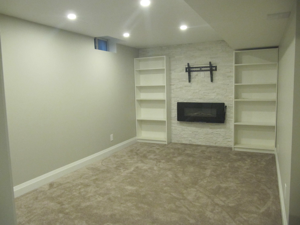 Small modern fully buried basement in Toronto with grey walls, carpet, a hanging fireplace, a stone fireplace surround and grey floor.