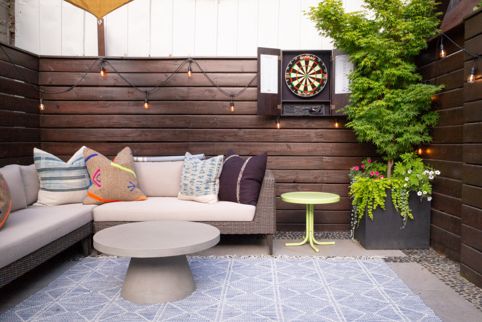 This is an example of a small eclectic backyard patio in Austin with a container garden, concrete slab and an awning.