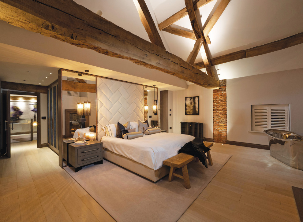 Mittelgroßes Modernes Hauptschlafzimmer mit weißer Wandfarbe, hellem Holzboden, Kamin, Kaminumrandung aus Stein, gewölbter Decke und Ziegelwänden in Cheshire