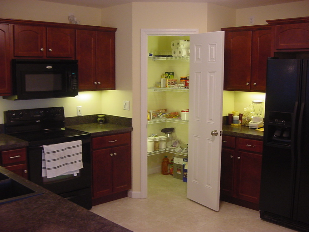 Inspiration for a traditional l-shaped kitchen pantry in Bridgeport with a double-bowl sink, recessed-panel cabinets, dark wood cabinets, laminate benchtops and black appliances.