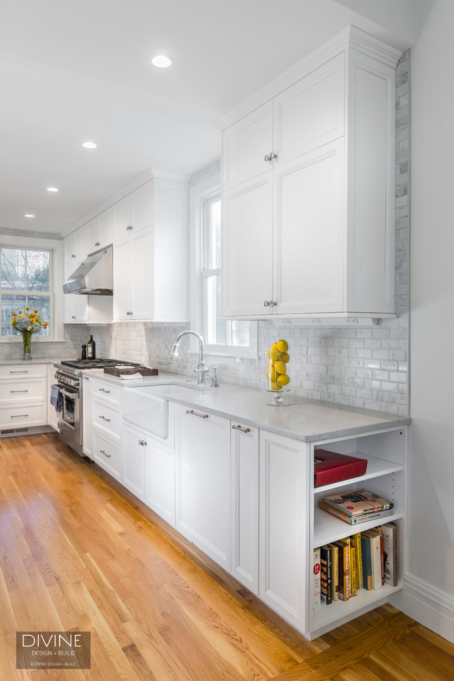 Example of a mid-sized transitional galley medium tone wood floor and brown floor eat-in kitchen design in Boston with a farmhouse sink, shaker cabinets, white cabinets, marble countertops, multicolored backsplash, marble backsplash, stainless steel appliances and an island