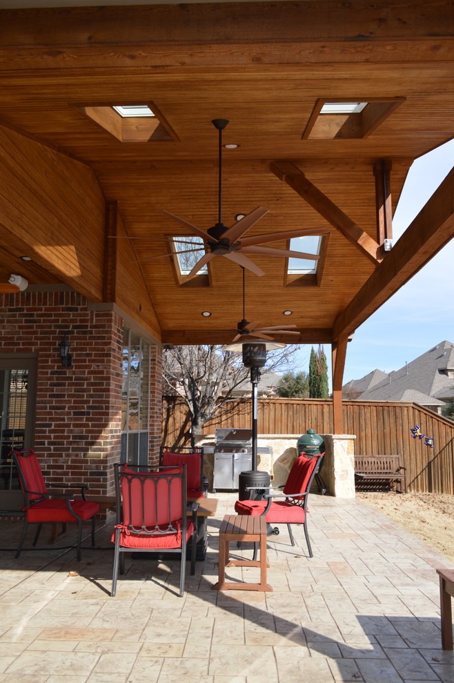 Design ideas for a large country backyard patio in Dallas with an outdoor kitchen, stamped concrete and a roof extension.