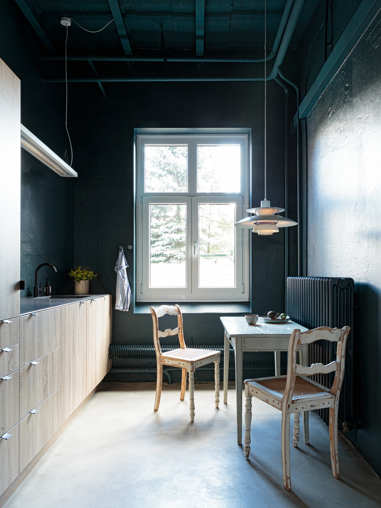 Inspiration for a small industrial single-wall separate kitchen in Hamburg with a drop-in sink, flat-panel cabinets, light wood cabinets, concrete floors, no island and grey floor.