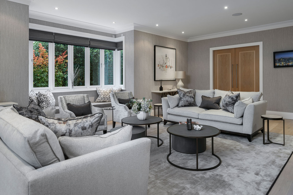 Photo of a large contemporary formal enclosed living room in Berkshire with beige walls, light hardwood flooring, a standard fireplace, no tv and wallpapered walls.
