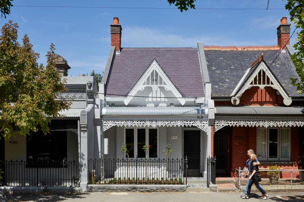 Mid-sized traditional two-storey grey house exterior in Melbourne with painted brick siding, a gable roof, a tile roof and a grey roof.