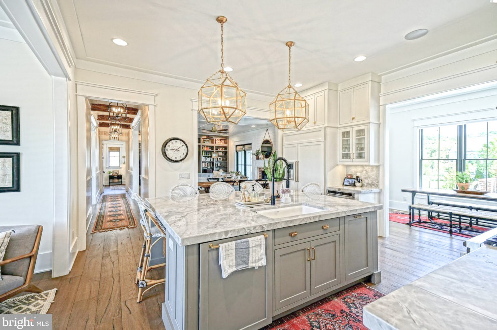 Inspiration for a large cottage medium tone wood floor and brown floor eat-in kitchen remodel in Other with a drop-in sink, shaker cabinets, white cabinets, marble countertops, gray backsplash, marble backsplash, paneled appliances, an island and gray countertops