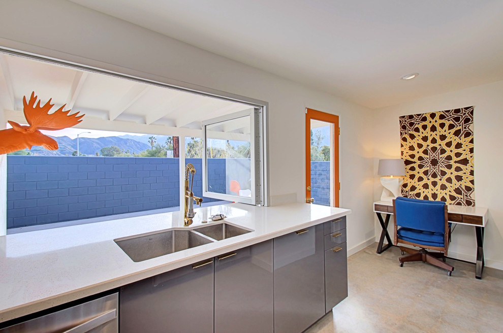 Inspiration for a mid-sized midcentury l-shaped open plan kitchen in Phoenix with an undermount sink, flat-panel cabinets, grey cabinets, quartz benchtops, yellow splashback, ceramic splashback, stainless steel appliances, concrete floors and a peninsula.