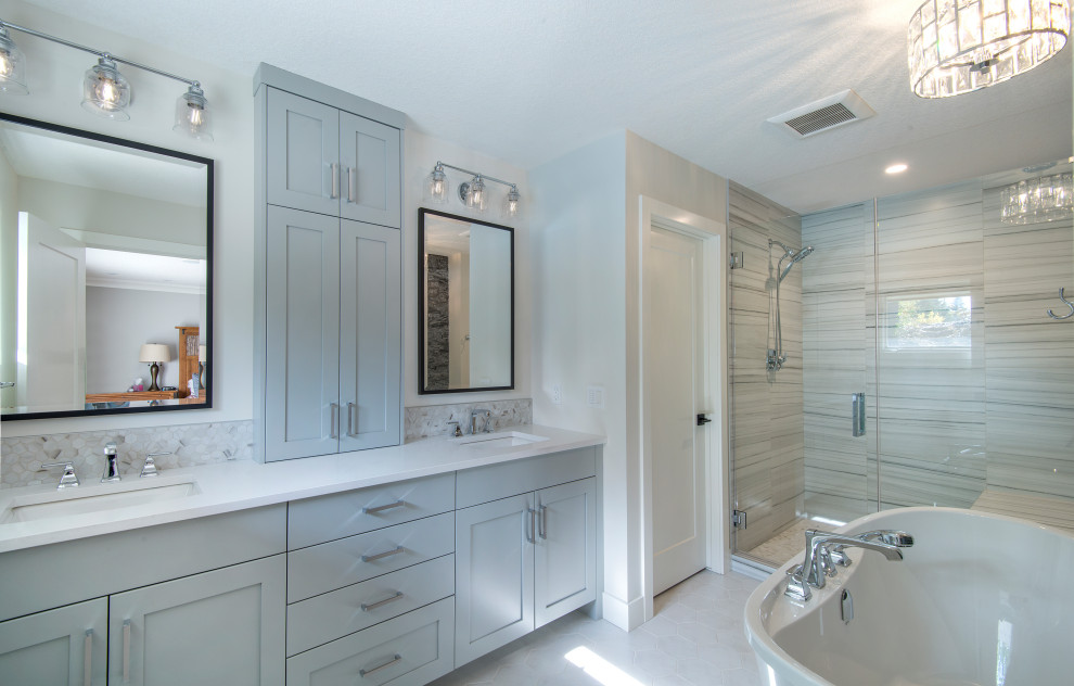 Aménagement d'une salle de bain principale moderne de taille moyenne avec un placard à porte shaker, des portes de placard grises, une baignoire indépendante, un carrelage gris, des carreaux de céramique, un mur blanc, un sol en carrelage de céramique, un plan de toilette en quartz, un sol blanc, une cabine de douche à porte battante, un plan de toilette blanc, meuble double vasque et meuble-lavabo encastré.