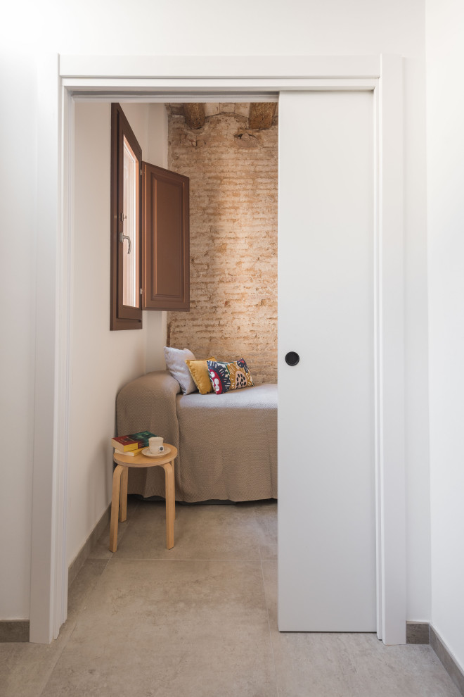 Immagine di una grande camera degli ospiti moderna con pareti bianche, pavimento con piastrelle in ceramica, pavimento beige, travi a vista e pareti in mattoni