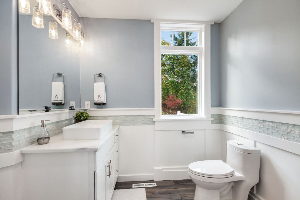 Photo of a small classic shower room bathroom in Seattle with shaker cabinets, white cabinets, a two-piece toilet, white tiles, glass tiles, blue walls, medium hardwood flooring, a vessel sink, granite worktops, grey floors, white worktops, an enclosed toilet, a single sink, a freestanding vanity unit and wainscoting.