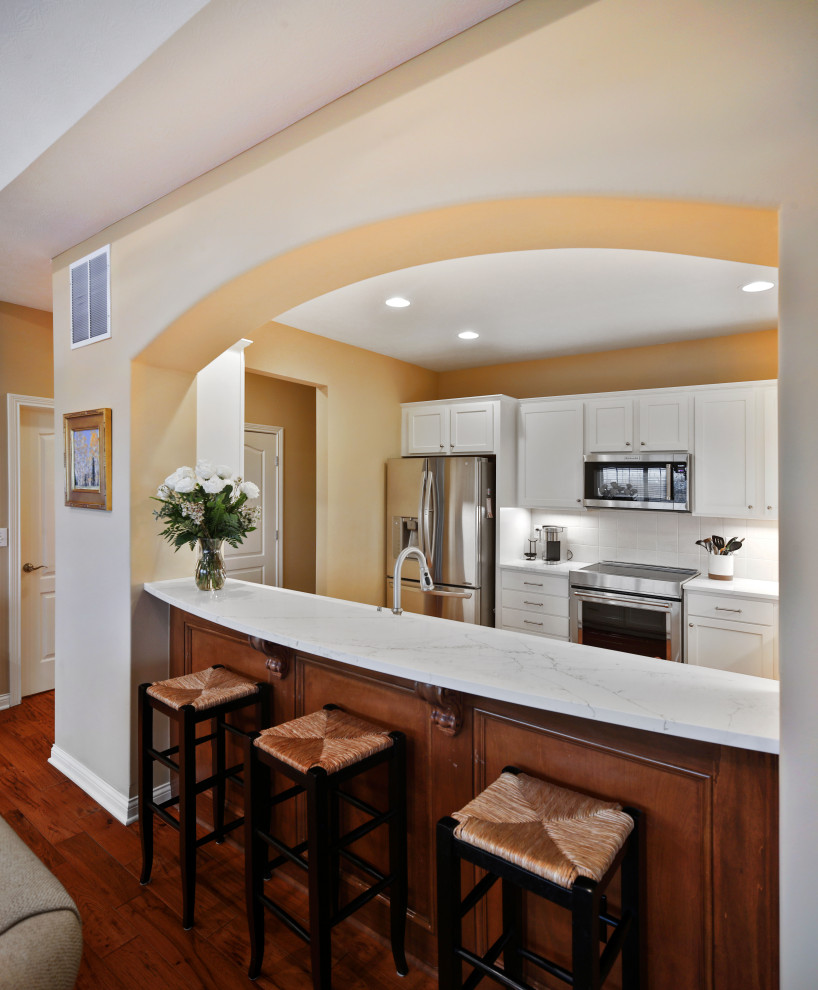 Inspiration for a mid-sized transitional galley medium tone wood floor and brown floor enclosed kitchen remodel in Columbus with a single-bowl sink, shaker cabinets, white cabinets, quartz countertops, white backsplash, ceramic backsplash, stainless steel appliances, no island and white countertops