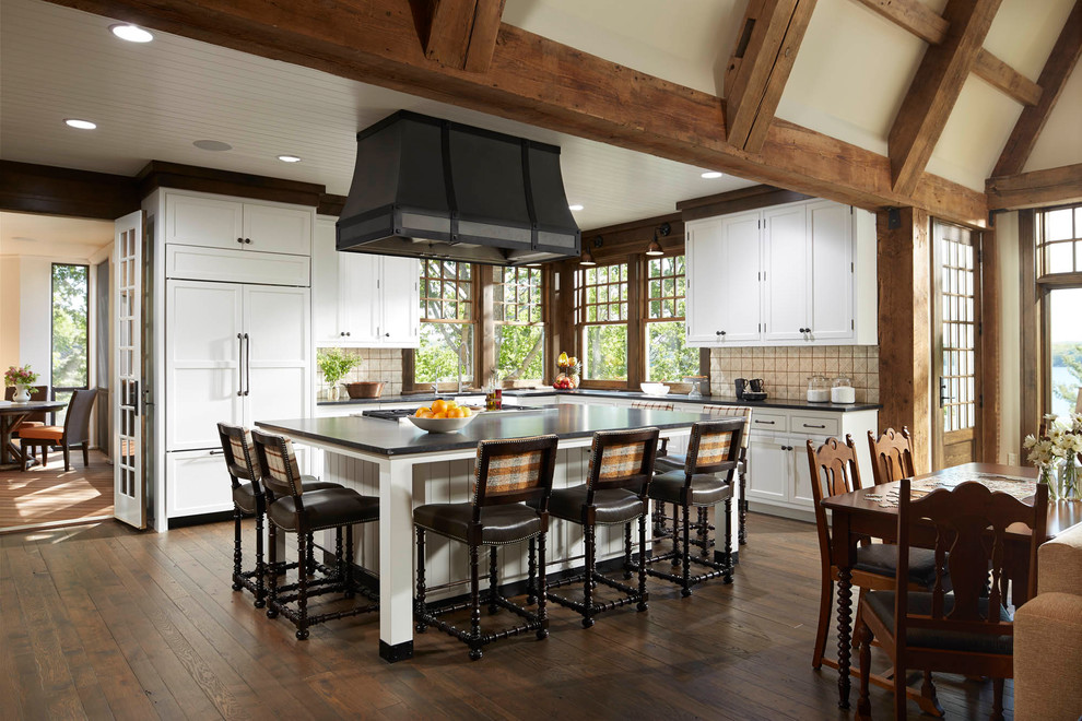 Inspiration for a country l-shaped kitchen in Minneapolis with shaker cabinets, white cabinets, beige splashback, white appliances, dark hardwood floors, with island and brown floor.