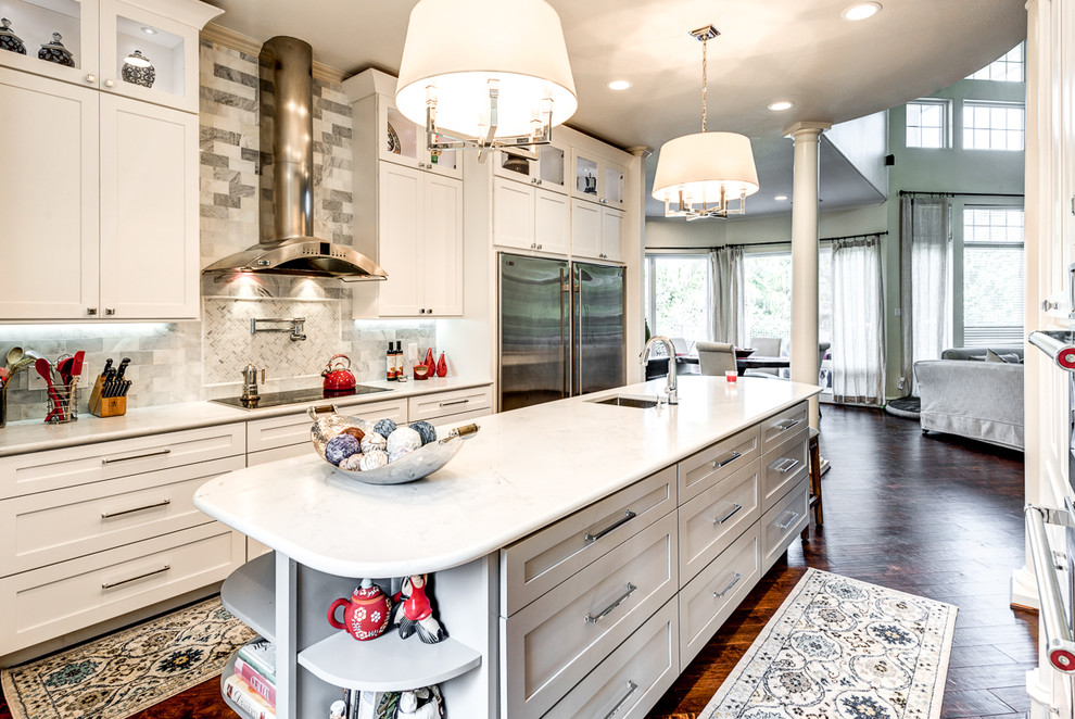 Design ideas for a large transitional l-shaped eat-in kitchen in Dallas with a drop-in sink, shaker cabinets, white cabinets, white splashback, marble splashback, stainless steel appliances, dark hardwood floors, with island, brown floor, quartz benchtops and white benchtop.
