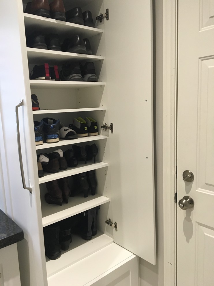 Small transitional galley dedicated laundry room in Toronto with an undermount sink, shaker cabinets, white cabinets, white walls, porcelain floors and a stacked washer and dryer.