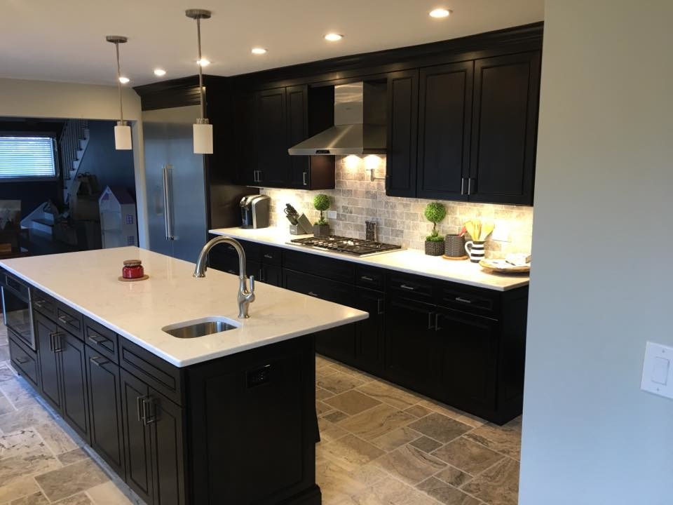 Example of a large transitional l-shaped porcelain tile and beige floor kitchen design in Chicago with an undermount sink, beaded inset cabinets, black cabinets, solid surface countertops, gray backsplash, stone tile backsplash, stainless steel appliances and an island
