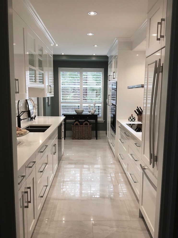 Photo of a mid-sized contemporary galley separate kitchen with an undermount sink, shaker cabinets, white cabinets, quartz benchtops, white splashback, ceramic splashback, stainless steel appliances, porcelain floors, no island and white floor.