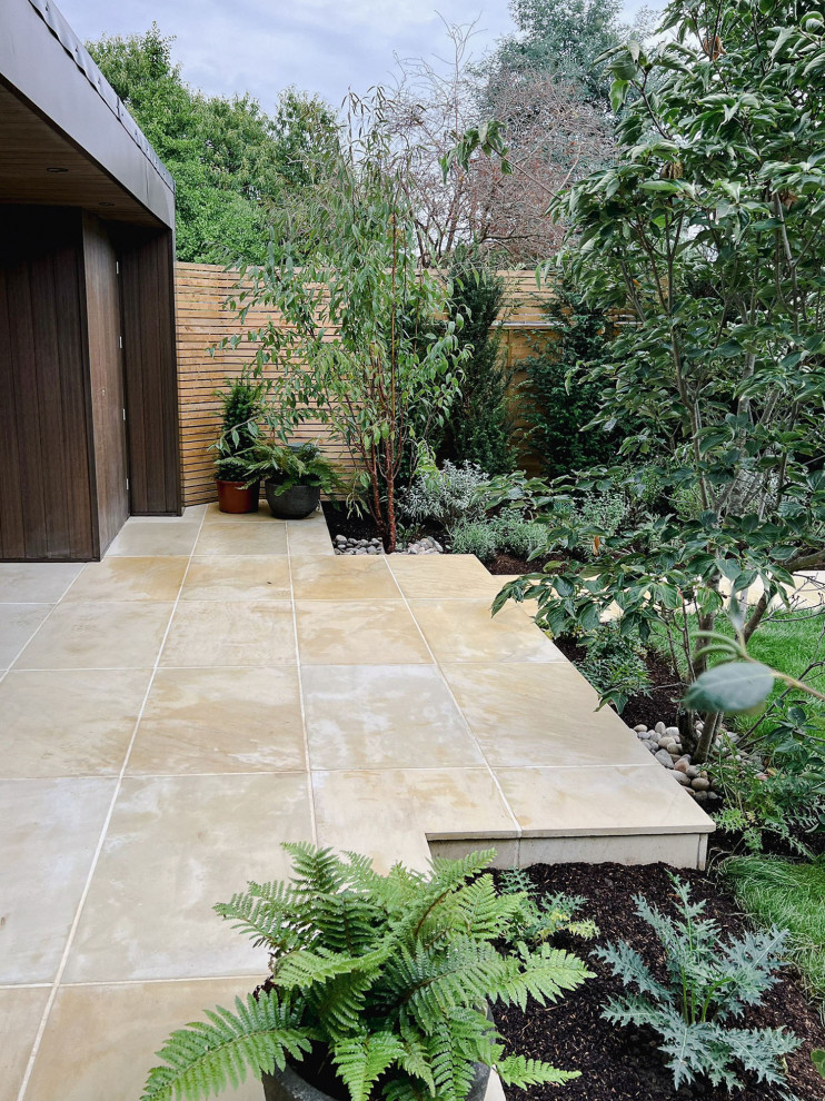 Design ideas for a medium sized contemporary back formal partial sun garden for summer in London with a pathway and natural stone paving.