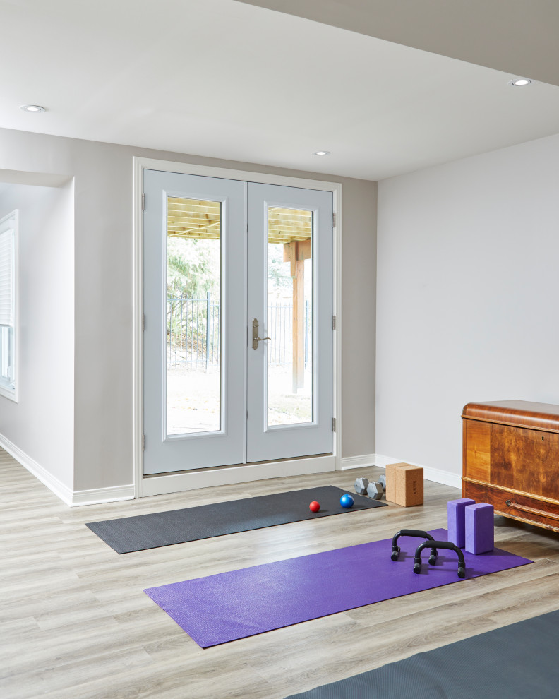 Mid-sized contemporary home yoga studio in Toronto with white walls, laminate floors and grey floor.