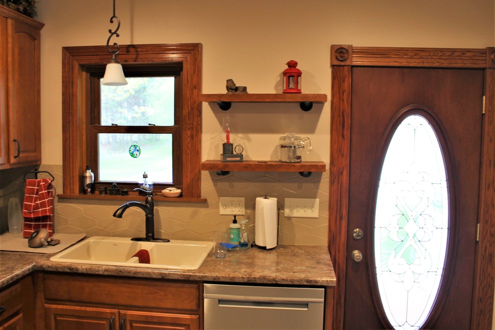 Mid-sized mountain style l-shaped vinyl floor and beige floor eat-in kitchen photo with a farmhouse sink, raised-panel cabinets, medium tone wood cabinets, laminate countertops, beige backsplash, cement tile backsplash, stainless steel appliances, a peninsula and beige countertops
