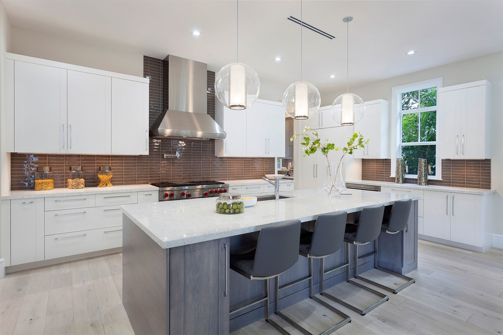 Example of a mid-sized trendy l-shaped light wood floor and beige floor open concept kitchen design in Miami with an undermount sink, flat-panel cabinets, medium tone wood cabinets, quartzite countertops, subway tile backsplash, stainless steel appliances, an island, multicolored countertops and brown backsplash