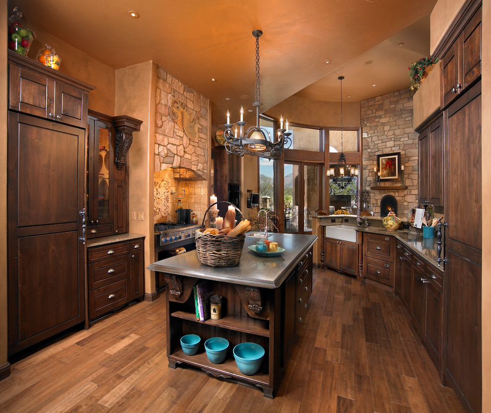 Mediterranean kitchen in Phoenix with a farmhouse sink, medium wood cabinets, panelled appliances, medium hardwood floors and with island.