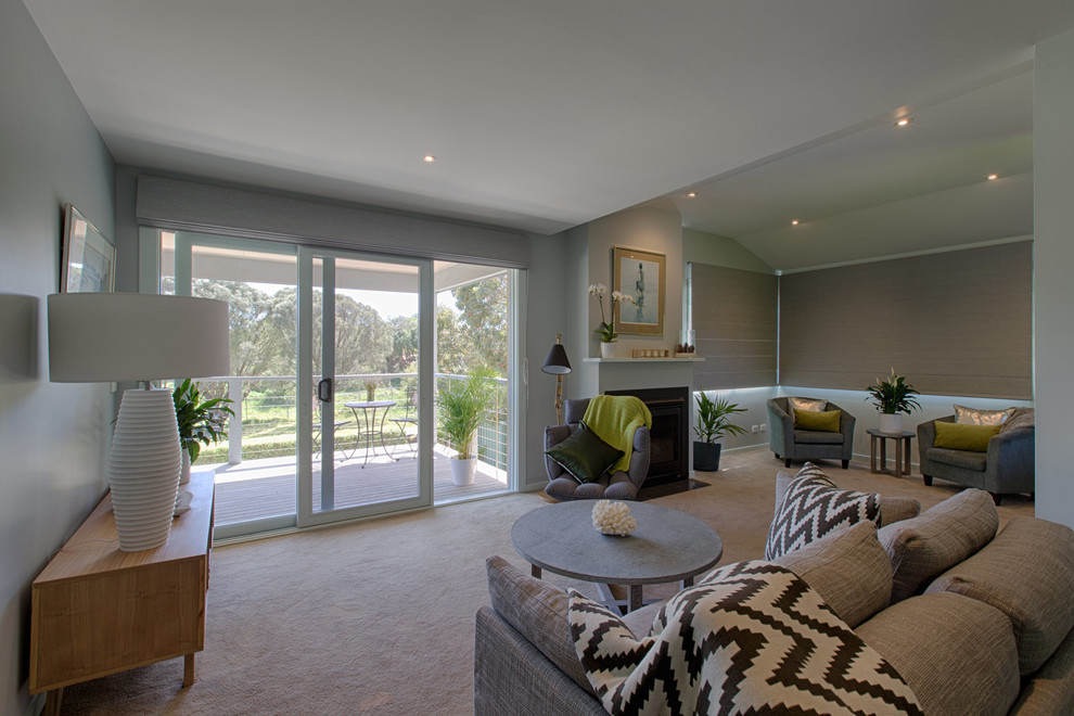 This is an example of a small beach style open concept family room in Melbourne with grey walls, carpet, a standard fireplace and a plaster fireplace surround.