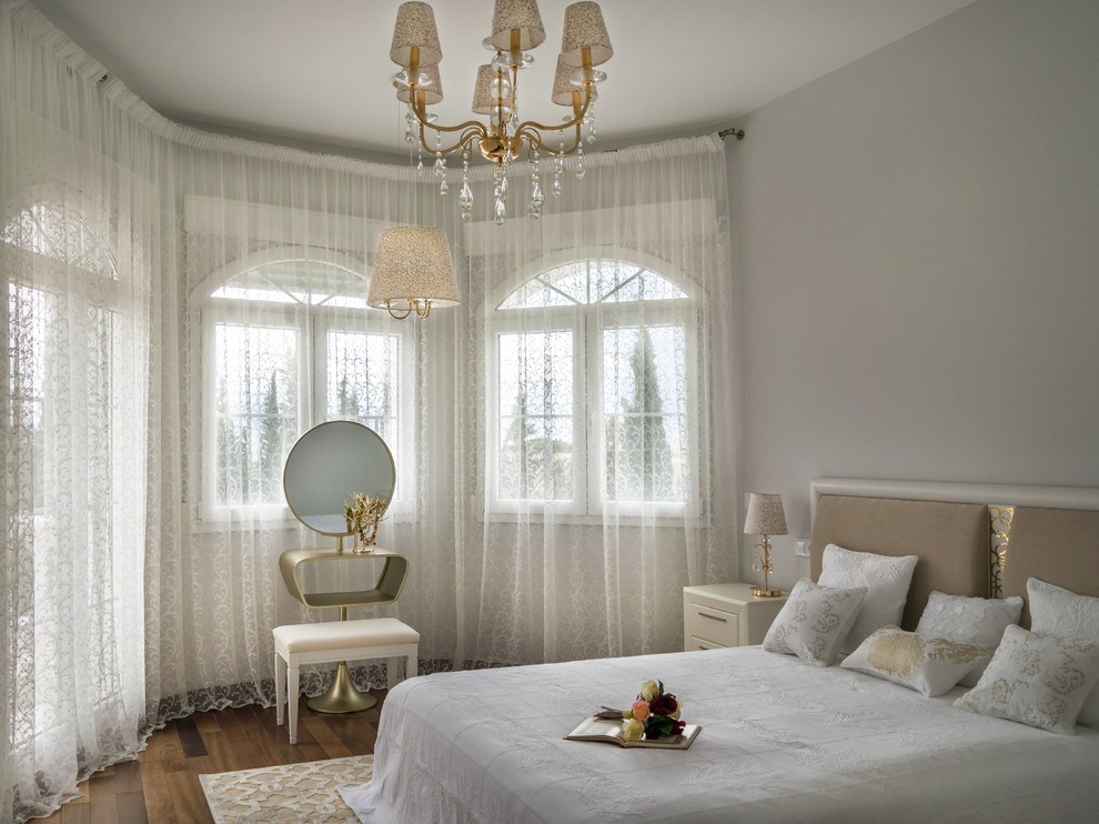 Imagen de dormitorio principal clásico renovado grande con paredes grises y suelo de madera en tonos medios