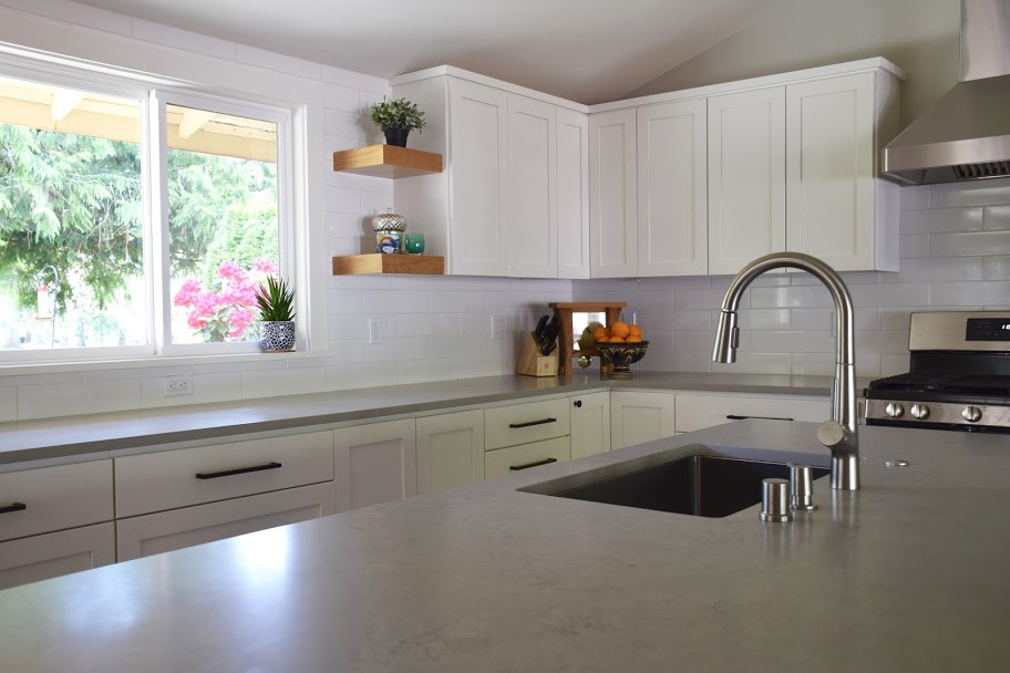 This is an example of a large contemporary l-shaped open plan kitchen in Seattle with an undermount sink, shaker cabinets, white cabinets, quartz benchtops, white splashback, subway tile splashback, stainless steel appliances, laminate floors, with island, multi-coloured floor, grey benchtop and vaulted.