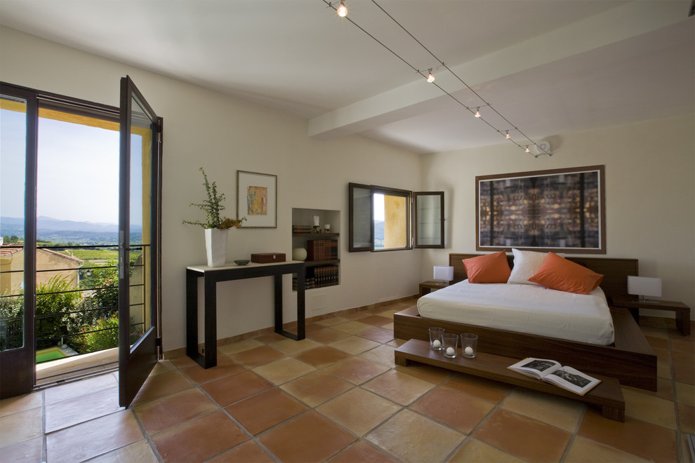 Mediterranean master bedroom in Marseille with beige walls, terra-cotta floors, no fireplace and orange floor.