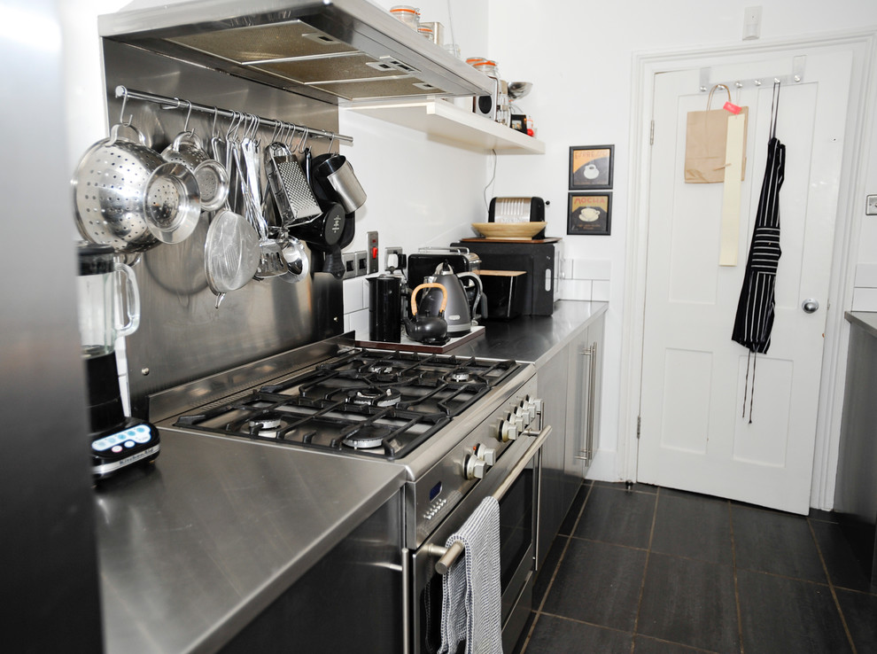 Contemporary kitchen in London with flat-panel cabinets, stainless steel cabinets, stainless steel worktops, metallic splashback, metal splashback and stainless steel appliances.