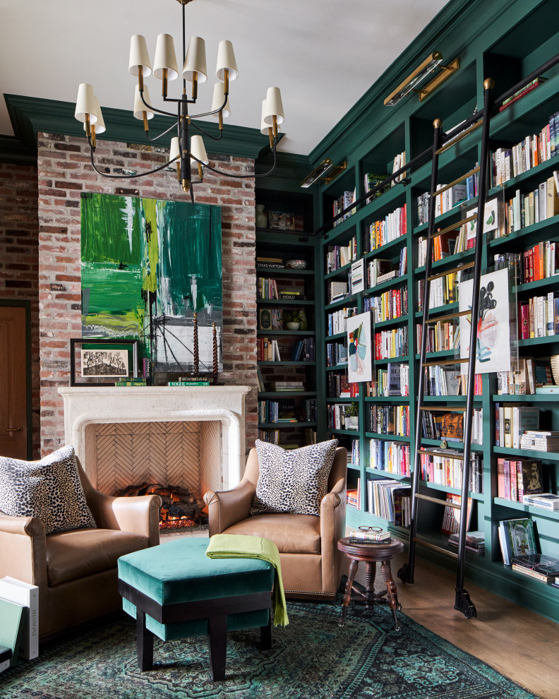 This is an example of a large transitional home office in Other with a library, green walls, medium hardwood floors, a standard fireplace, a freestanding desk, brown floor and brick walls.