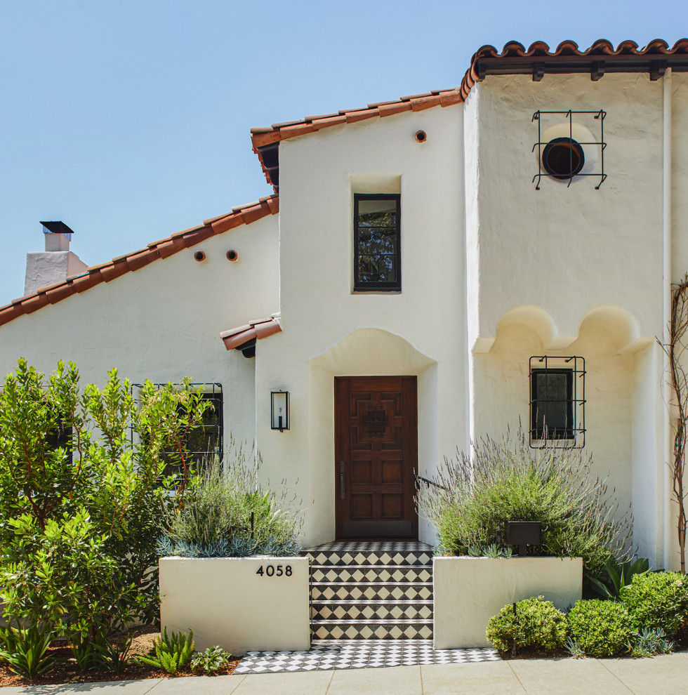 Photo of a large and white mediterranean render detached house in Los Angeles with three floors, a lean-to roof, a tiled roof and a red roof.