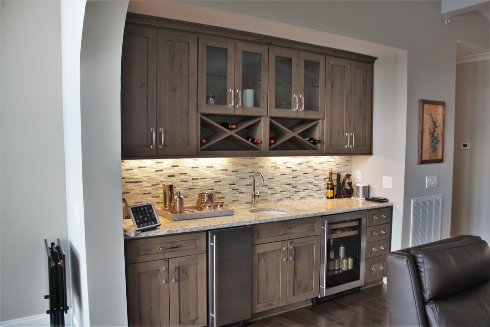 Photo of a beach style home bar in Charlotte with shaker cabinets, medium wood cabinets, quartz benchtops and mosaic tile splashback.