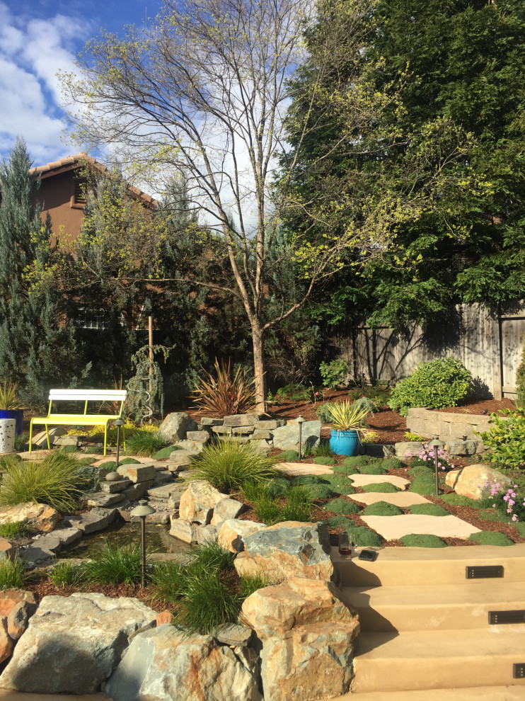 Пример оригинального дизайна: солнечный, летний засухоустойчивый сад на заднем дворе в средиземноморском стиле с камнем в ландшафтном дизайне, хорошей освещенностью и покрытием из каменной брусчатки