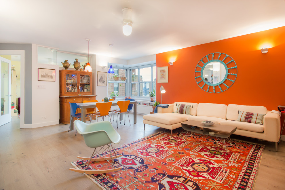 This is an example of a contemporary open concept family room in New York with orange walls and light hardwood floors.