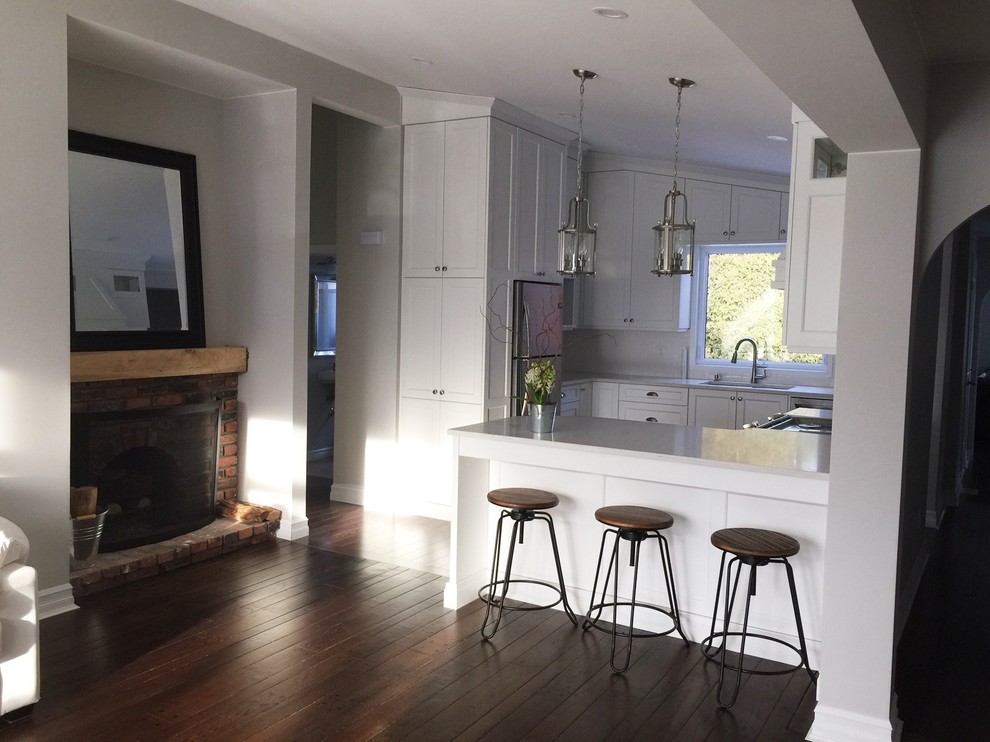 Small transitional u-shaped medium tone wood floor and brown floor kitchen photo in Toronto with flat-panel cabinets, white cabinets, quartz countertops, white backsplash, ceramic backsplash, stainless steel appliances and a peninsula