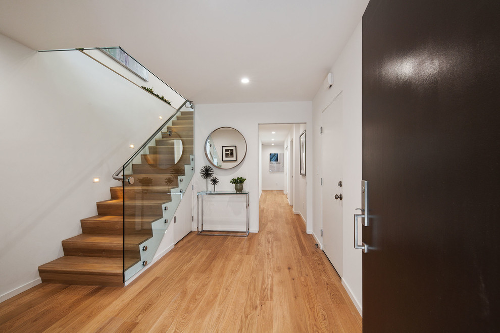 Design ideas for a mid-sized contemporary foyer in San Francisco with white walls, medium hardwood floors, a single front door, a brown front door and brown floor.