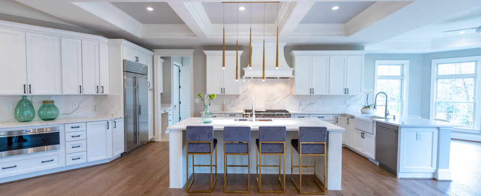 Inspiration for a huge transitional u-shaped light wood floor, brown floor and tray ceiling eat-in kitchen remodel with an undermount sink, shaker cabinets, white cabinets, quartz countertops, white backsplash, quartz backsplash, stainless steel appliances, an island and white countertops