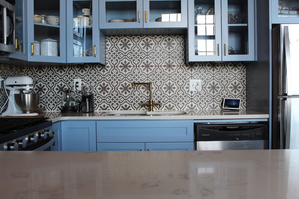 Eat-in kitchen - mid-sized transitional u-shaped concrete floor and beige floor eat-in kitchen idea in Atlanta with an undermount sink, glass-front cabinets, blue cabinets, quartzite countertops, multicolored backsplash, ceramic backsplash, stainless steel appliances, a peninsula and white countertops