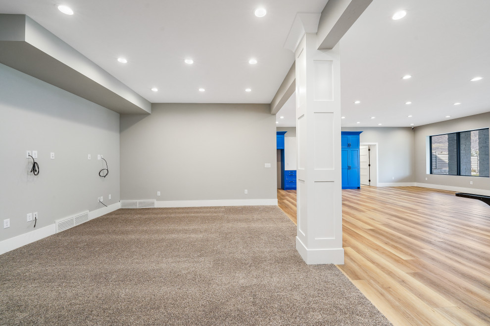 На фото: большой подвал в стиле модернизм с выходом наружу, игровой комнатой, серыми стенами, паркетным полом среднего тона, коричневым полом и балками на потолке с