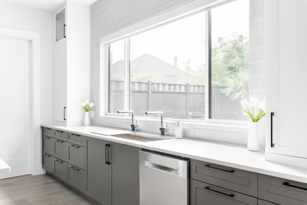 Inspiration for a large transitional u-shaped medium tone wood floor and brown floor open concept kitchen remodel in Vancouver with an undermount sink, shaker cabinets, gray cabinets, quartz countertops, gray backsplash, stone slab backsplash, stainless steel appliances, an island and gray countertops