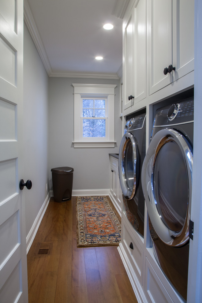 Photo of a traditional laundry room in Other with marble benchtops, grey walls, dark hardwood floors, an integrated washer and dryer and black benchtop.