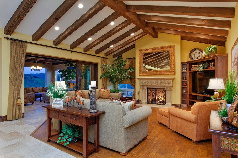 Mediterranean formal living room in San Diego with yellow walls, medium hardwood floors and a standard fireplace.