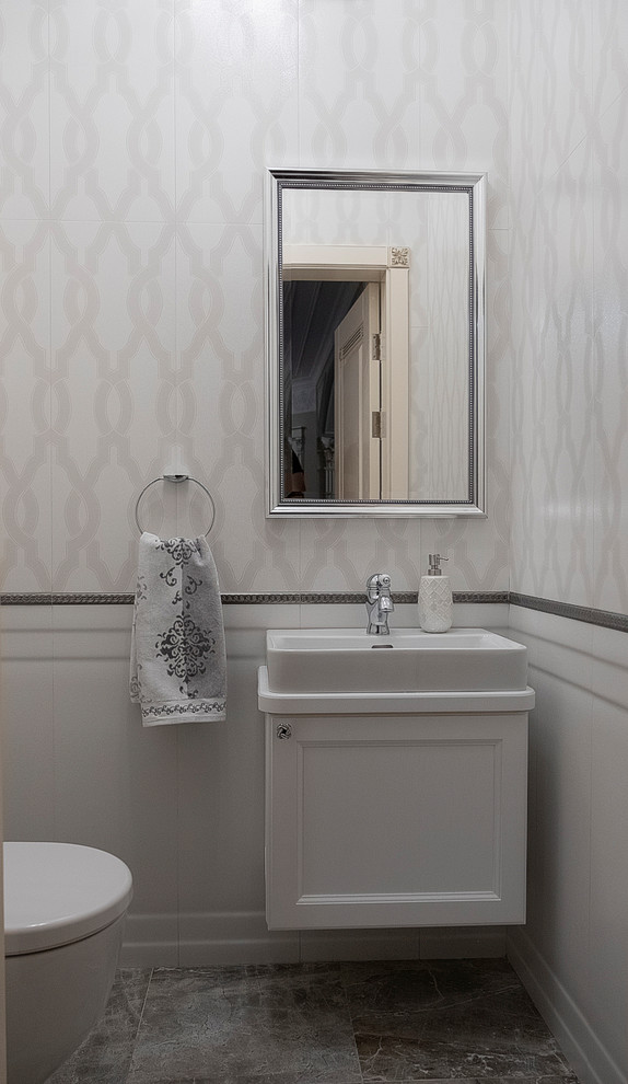 Photo of a small transitional powder room in Other with recessed-panel cabinets, white cabinets, a wall-mount toilet, gray tile, grey walls, porcelain floors, a drop-in sink, solid surface benchtops, grey floor and white benchtops.