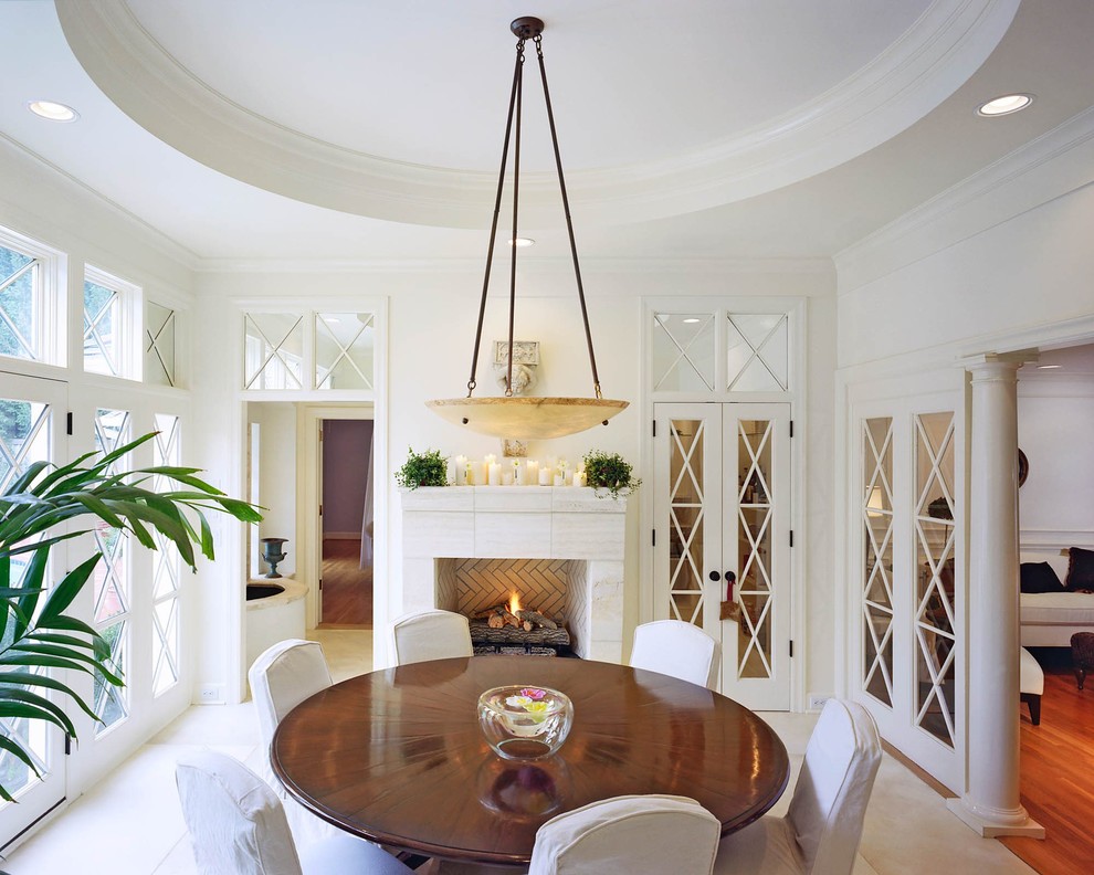 Mid-sized traditional separate dining room in Charlotte with white walls, limestone floors, a standard fireplace, a tile fireplace surround and beige floor.