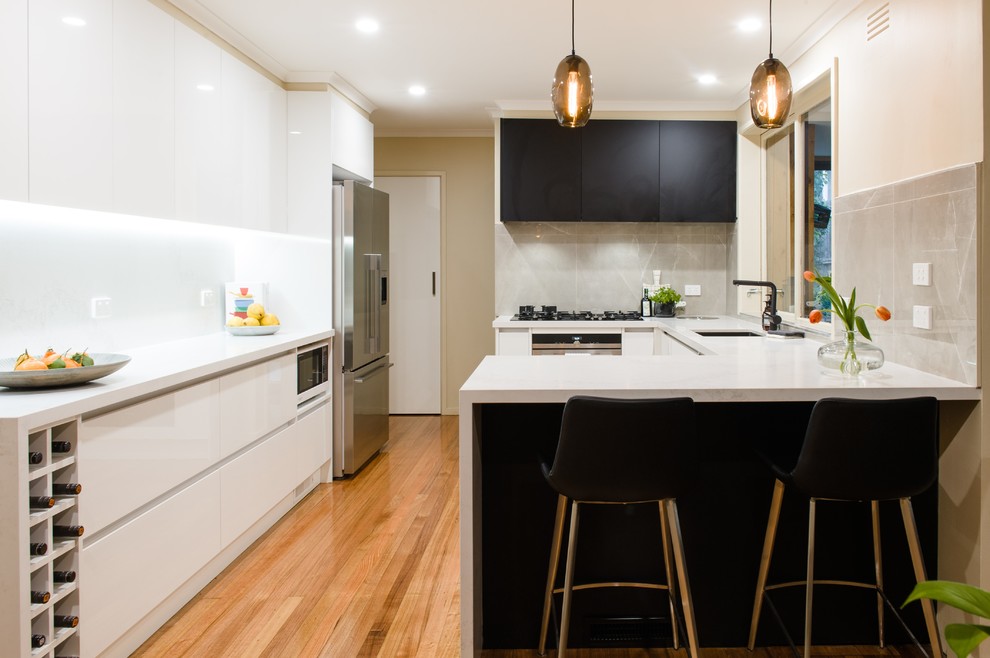 Mid-sized modern l-shaped kitchen pantry in Melbourne with an undermount sink, open cabinets, black cabinets, solid surface benchtops, mosaic tile splashback, stainless steel appliances, medium hardwood floors and with island.